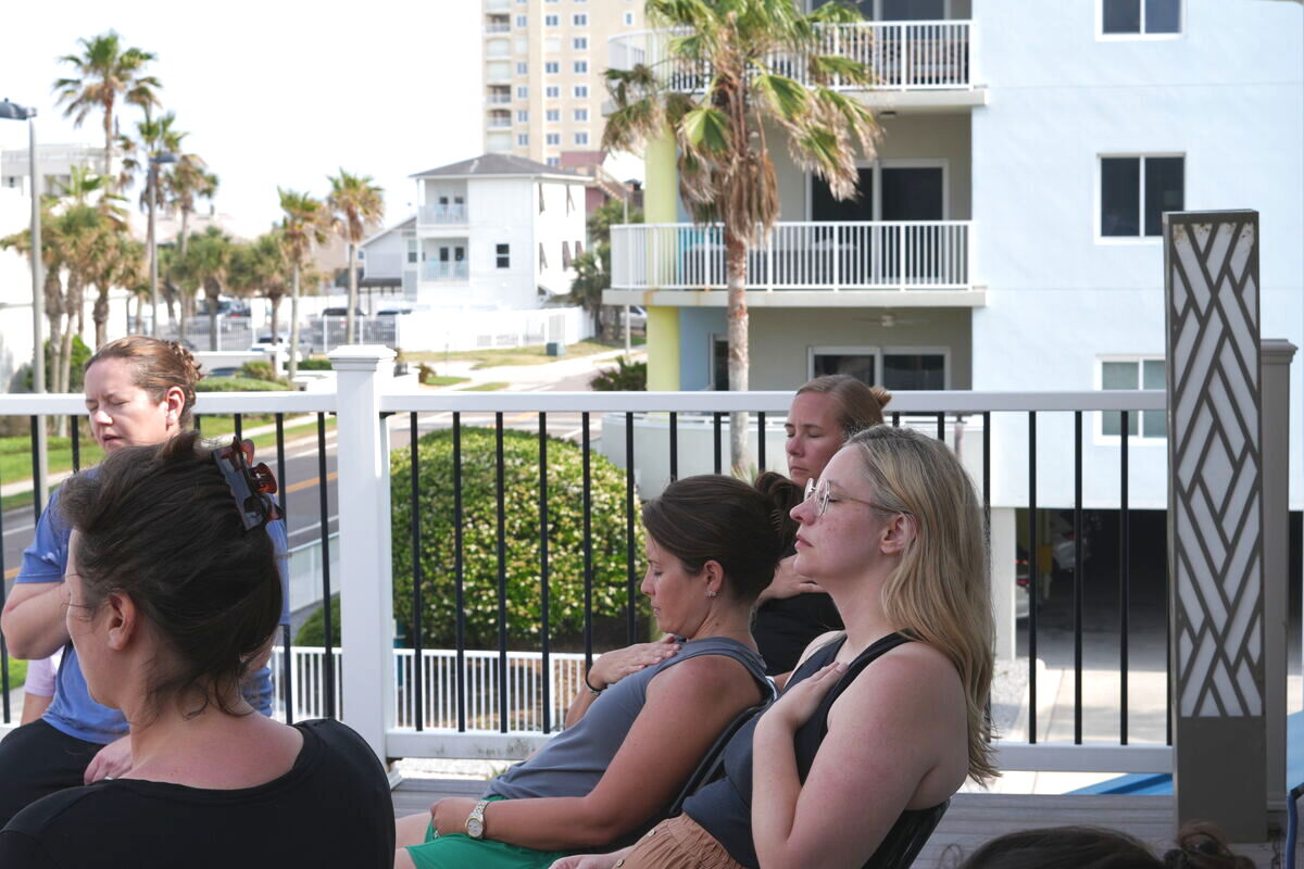 Women meditating together on the oceanfront deck